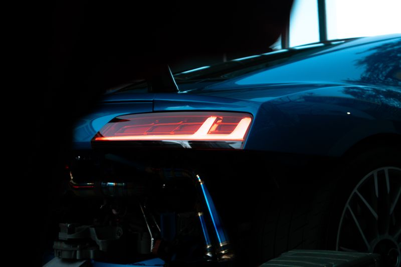 A close crop of a dark BMW M4 tail light glowing orange against almost total blackness.